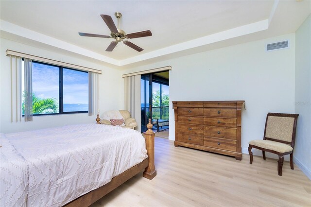 bedroom featuring a raised ceiling, ceiling fan, access to outside, and light wood-type flooring