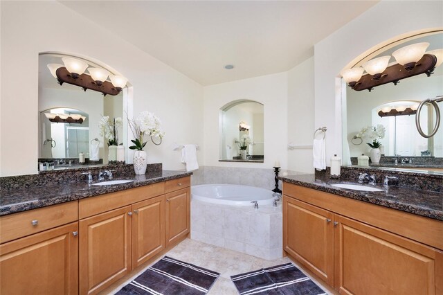 bathroom with tile patterned flooring, vanity, and a relaxing tiled tub