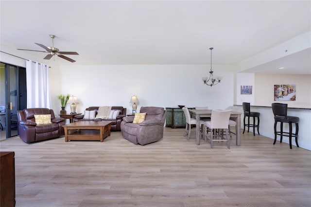 living room with ceiling fan with notable chandelier and light hardwood / wood-style floors