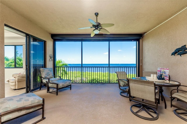 sunroom / solarium with a water view, ceiling fan, and a healthy amount of sunlight