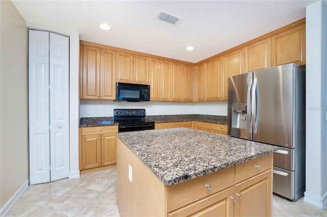 kitchen with dark stone countertops, a kitchen island, black appliances, and light tile patterned floors