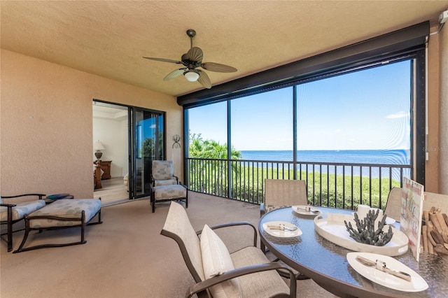 sunroom featuring a water view and ceiling fan