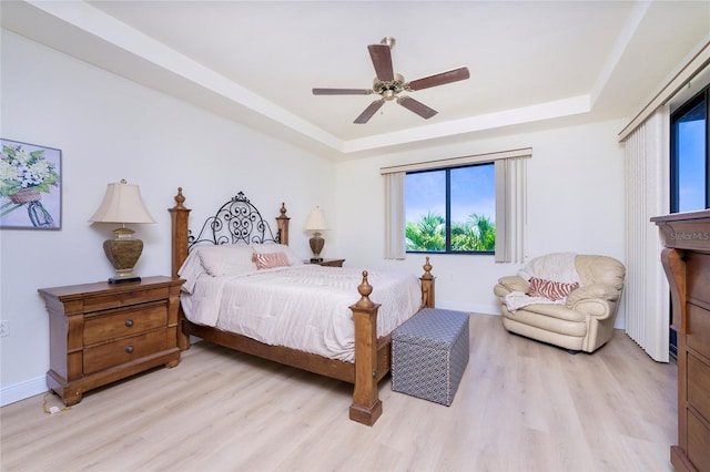 bedroom with a raised ceiling, ceiling fan, and light hardwood / wood-style flooring