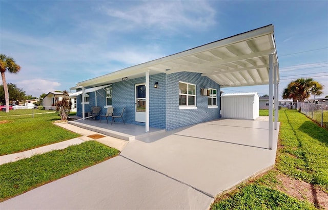 view of front of house with a front yard, fence, an attached carport, and brick siding