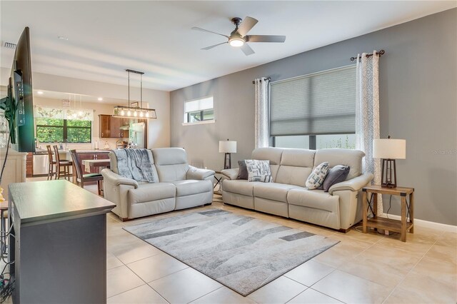 tiled living room with ceiling fan with notable chandelier