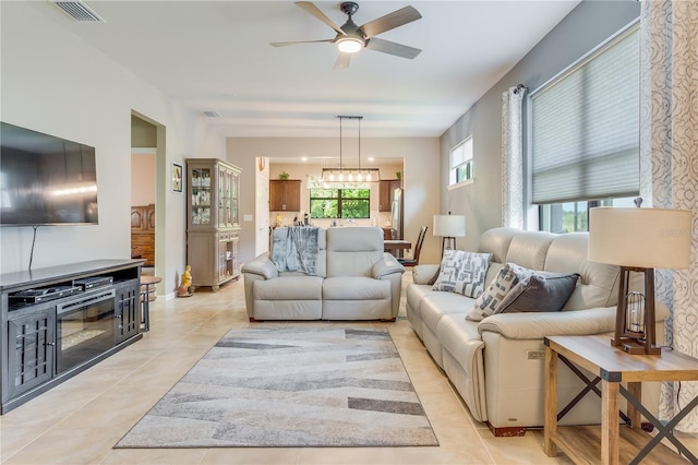 living room with ceiling fan with notable chandelier and light tile patterned floors