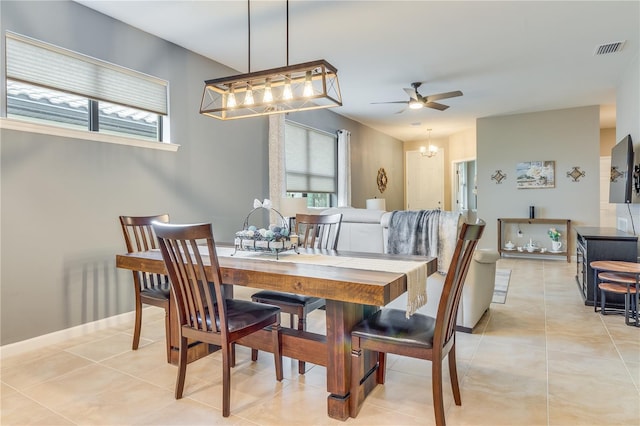 tiled dining space with ceiling fan with notable chandelier