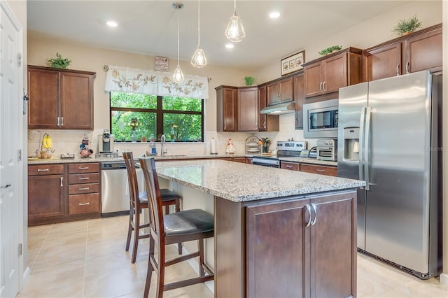 kitchen with a kitchen island, tasteful backsplash, stainless steel appliances, and light tile patterned floors