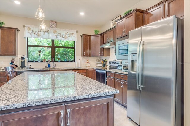 kitchen with tasteful backsplash, light tile patterned floors, stainless steel appliances, light stone countertops, and sink