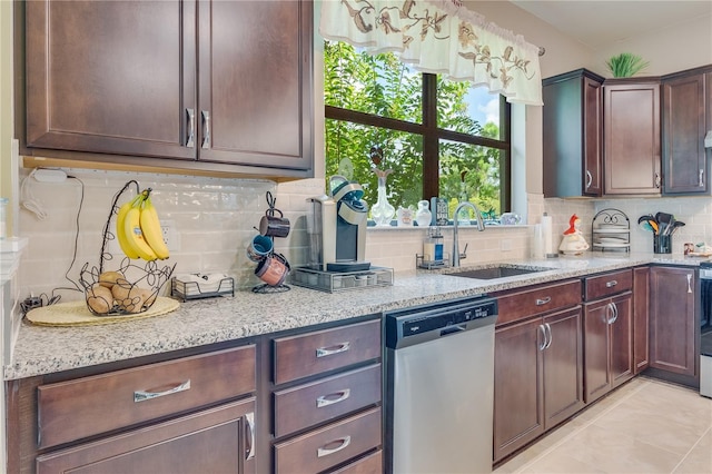 kitchen with tasteful backsplash, sink, light stone counters, light tile patterned floors, and stainless steel dishwasher