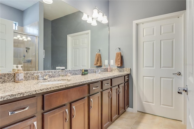 bathroom featuring a shower with shower door, double vanity, and tile patterned flooring