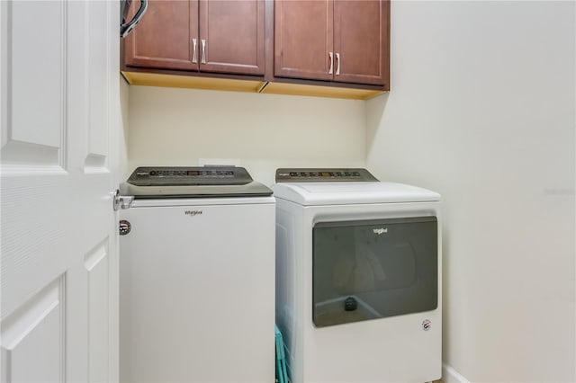 clothes washing area featuring washing machine and dryer and cabinets