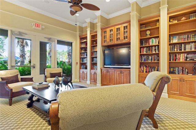 carpeted living room featuring built in shelves, ornate columns, crown molding, and ceiling fan