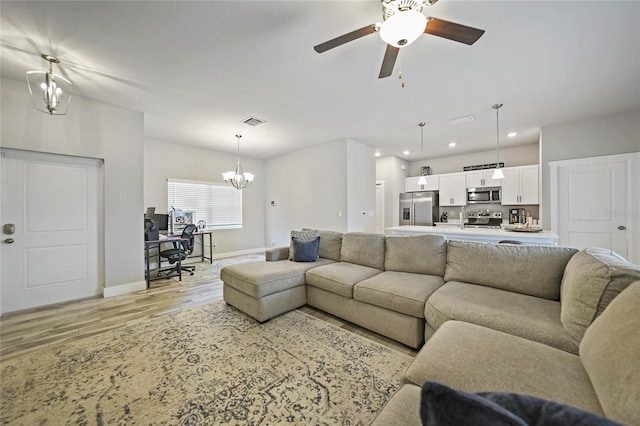 living room featuring light wood-type flooring and ceiling fan with notable chandelier