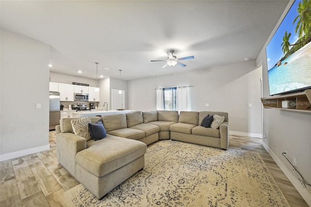 living room featuring sink, light hardwood / wood-style flooring, and ceiling fan