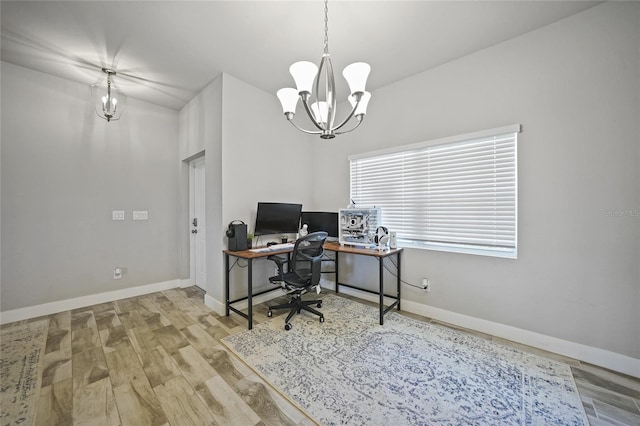 office with light hardwood / wood-style flooring and a notable chandelier