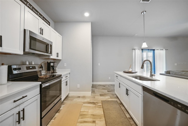 kitchen with light countertops, appliances with stainless steel finishes, a sink, and white cabinets