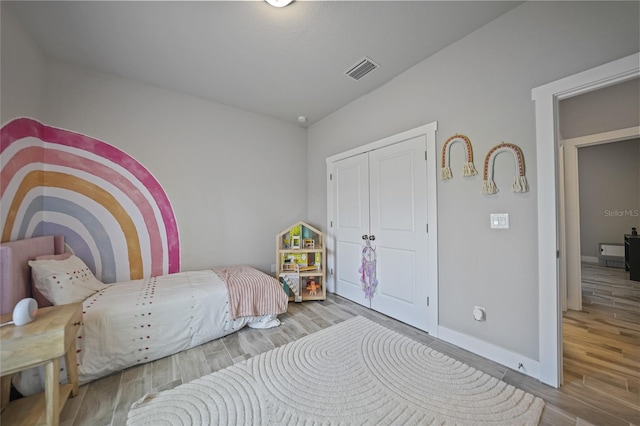 bedroom with baseboards, a closet, visible vents, and wood finished floors