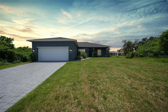 view of front of house featuring a garage, stucco siding, decorative driveway, and a yard