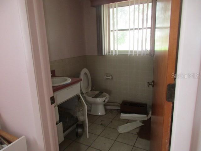 bathroom with vanity, tile patterned flooring, toilet, and tile walls