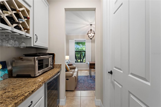 kitchen featuring an inviting chandelier, stone countertops, white cabinets, light tile patterned flooring, and beverage cooler