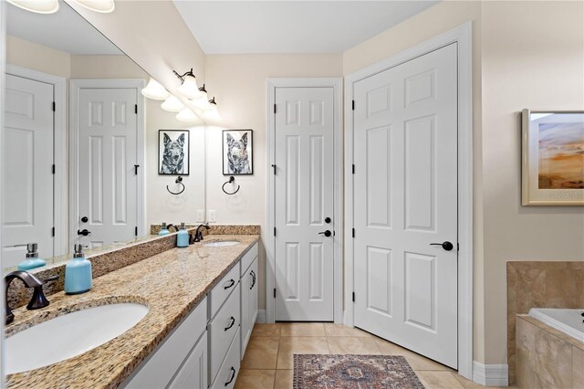 bathroom featuring tiled tub, double vanity, and tile patterned floors