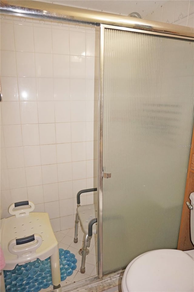 bathroom with tile patterned flooring, toilet, and a shower with door