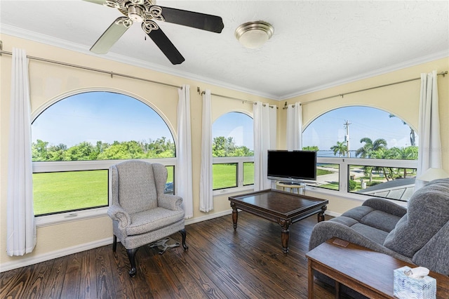 living area with ceiling fan, dark hardwood / wood-style flooring, a textured ceiling, and ornamental molding