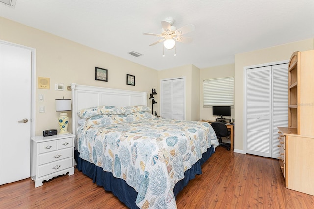 bedroom featuring ceiling fan, two closets, and hardwood / wood-style flooring