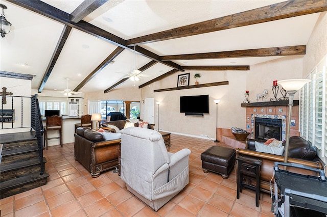 tiled living room with a tiled fireplace, ceiling fan, and vaulted ceiling with beams