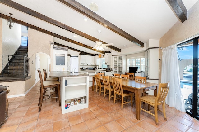 tiled dining space with ceiling fan, sink, and vaulted ceiling with beams