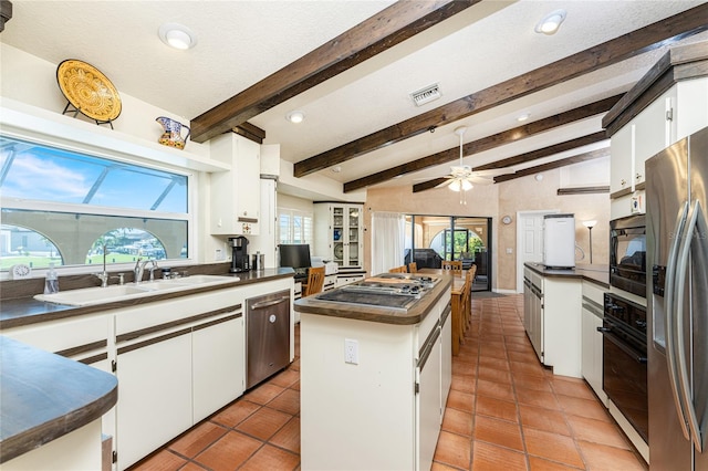 kitchen featuring white cabinets, a center island, stainless steel appliances, a wealth of natural light, and vaulted ceiling with beams