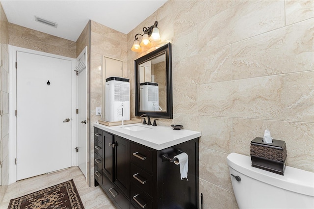 bathroom featuring vanity, toilet, and tile walls