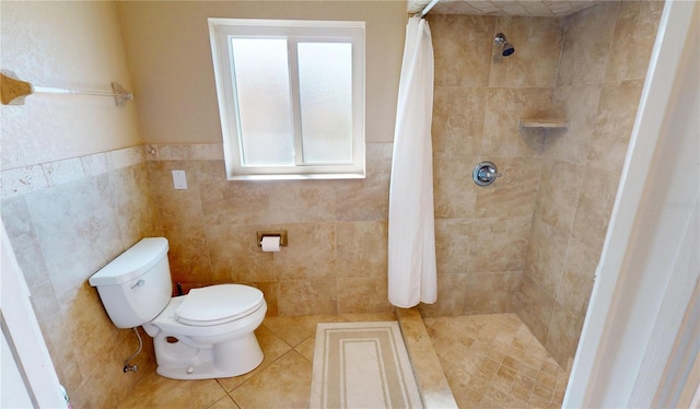 bathroom with curtained shower, tile patterned floors, tile walls, and toilet