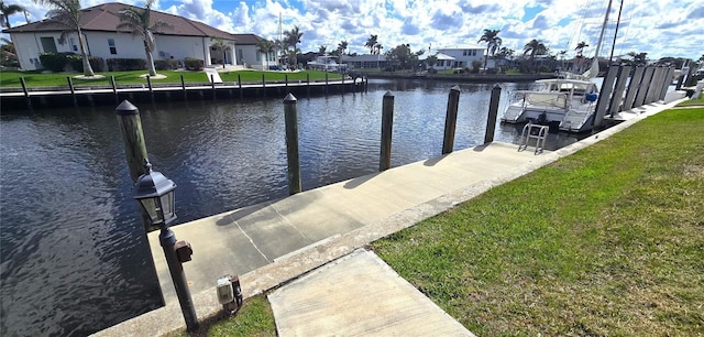 view of dock with a lawn and a water view