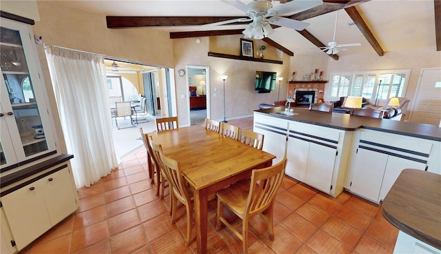 dining room featuring sink, light tile patterned floors, ceiling fan, a fireplace, and lofted ceiling with beams