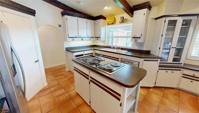 kitchen featuring sink, a center island, white cabinets, light tile patterned flooring, and stainless steel gas stovetop