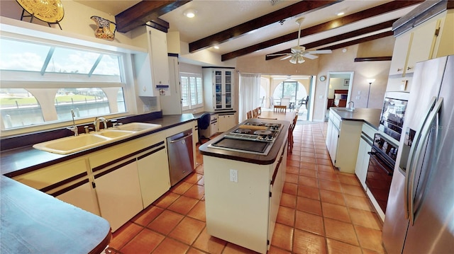 kitchen with lofted ceiling with beams, appliances with stainless steel finishes, white cabinets, and a kitchen island