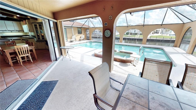 view of swimming pool with an in ground hot tub, sink, a patio area, and glass enclosure