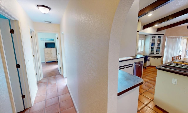 hallway featuring light tile patterned floors and beam ceiling