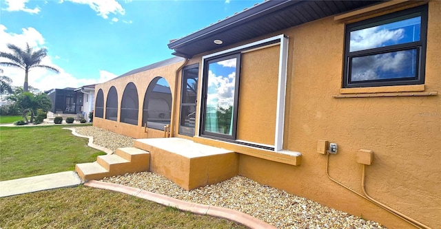 view of side of property with a lawn and a sunroom