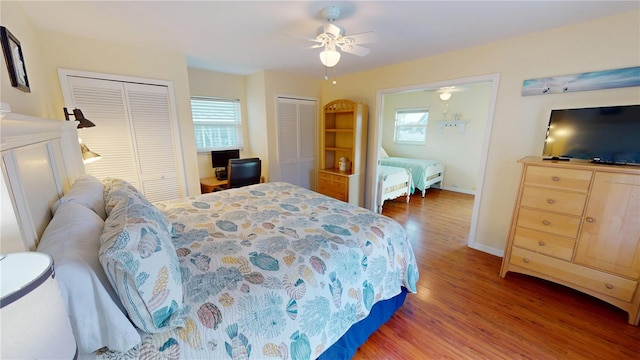 bedroom featuring multiple closets, ceiling fan, dark hardwood / wood-style floors, and multiple windows