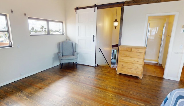 sitting room featuring dark wood-type flooring and a barn door