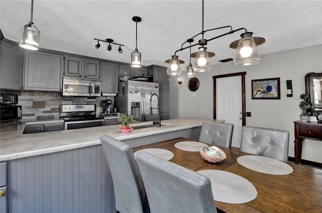 kitchen with stainless steel appliances, decorative light fixtures, tasteful backsplash, and gray cabinetry