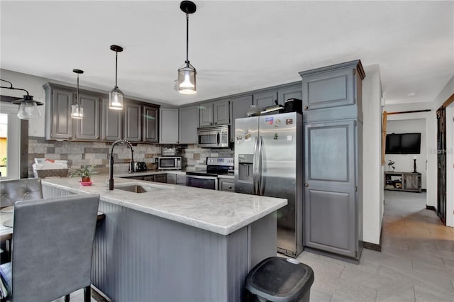 kitchen featuring kitchen peninsula, backsplash, hanging light fixtures, appliances with stainless steel finishes, and sink