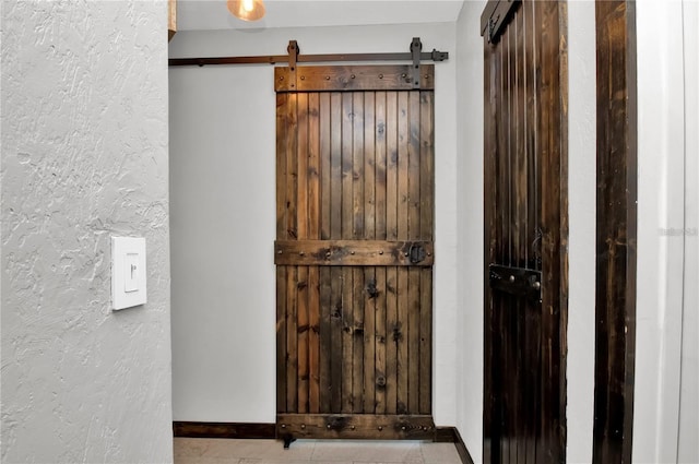 details with a textured wall, baseboards, and a barn door