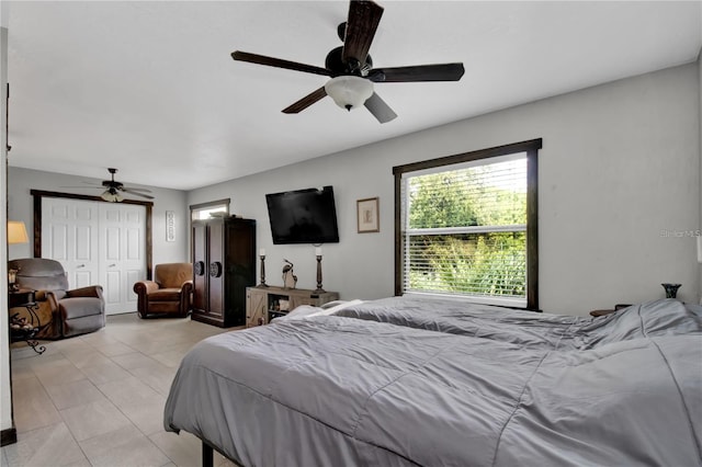 bedroom featuring ceiling fan, light tile patterned floors, and a closet