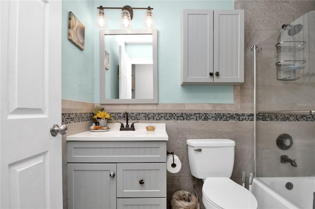 bathroom featuring shower / tub combination, toilet, vanity, tile walls, and wainscoting