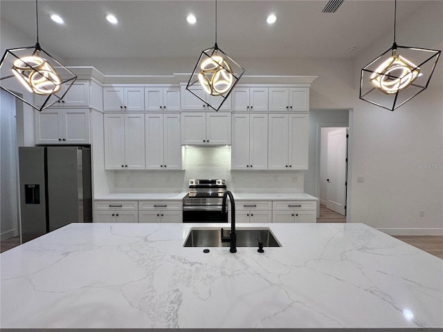 kitchen with light stone counters, stainless steel appliances, and hanging light fixtures