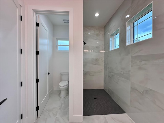 bathroom featuring a healthy amount of sunlight, a tile shower, and toilet